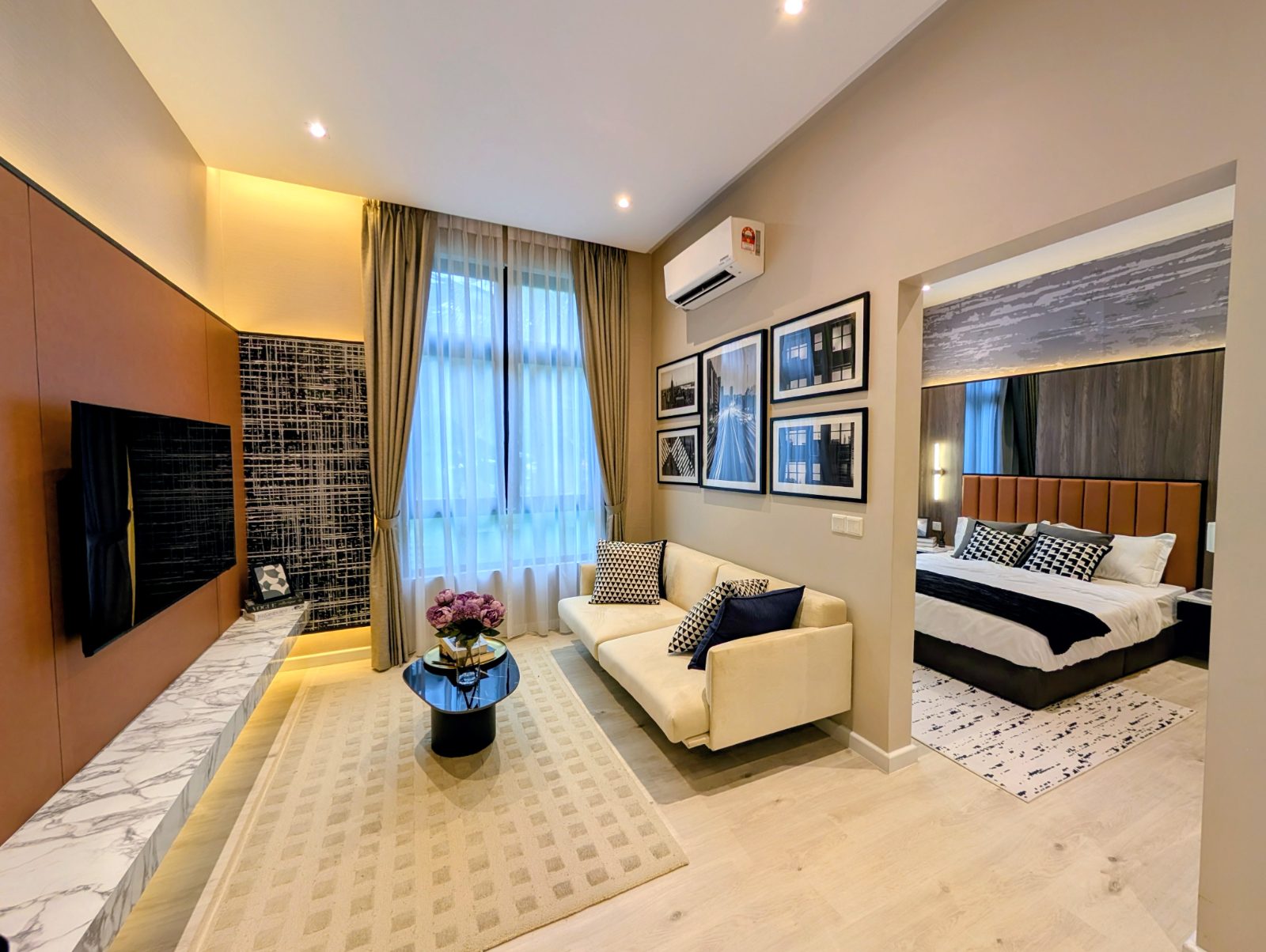 Show unit living area with sofa, gallery wall and bedroom beyond